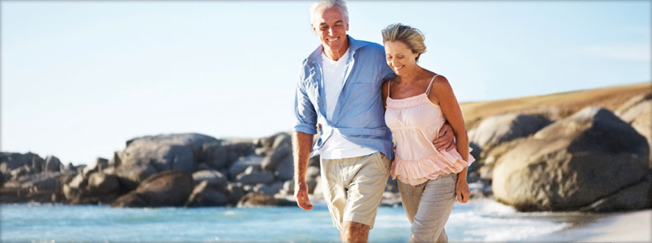 retired couple walking on beach